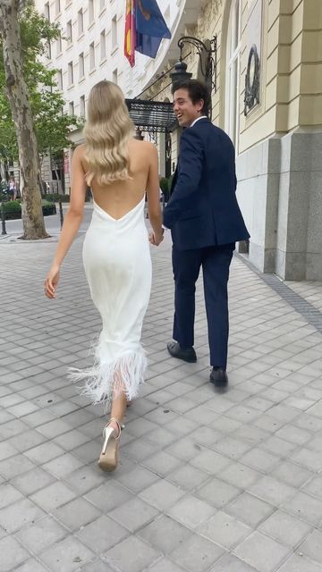 a man and woman are walking down the street in front of a building with flags on it