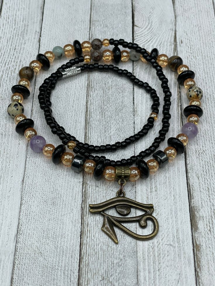 "🌟 Welcome to our shop! 🔥 ✨ Our handmade \"I am Protected\" Waist Beads with Eye of Horus Charm are the perfect blend of tradition and spirituality. ✨ 💎 Made with the highest quality materials and crafted with care, our waist beads are stretchy and come with a clasp for easy wearing and adjusting. They feature a beautiful Eye of Horus charm and multiple crystals including Amethyst, Hematite, Jasper, and Tiger Eye. Each of these crystals holds powerful energy that can enhance your spiritual jo Gold Amethyst Jewelry With 8mm Beads, Spiritual Amethyst Bead Jewelry, Spiritual Amethyst 8mm Beads Jewelry, Spiritual Amethyst Jewelry With 8mm Beads, Black Amethyst Beads Jewelry 8mm, Black Amethyst 8mm Bead Jewelry, Adjustable Jewelry With Polished Oval Beads, Symbolic Gold Beaded Jewelry, Spiritual Hand-strung Amethyst Jewelry