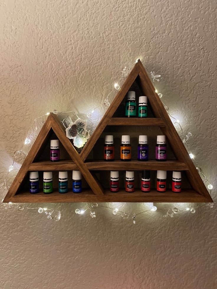 a wooden shelf filled with bottles of essential oils on top of a wall next to a candle