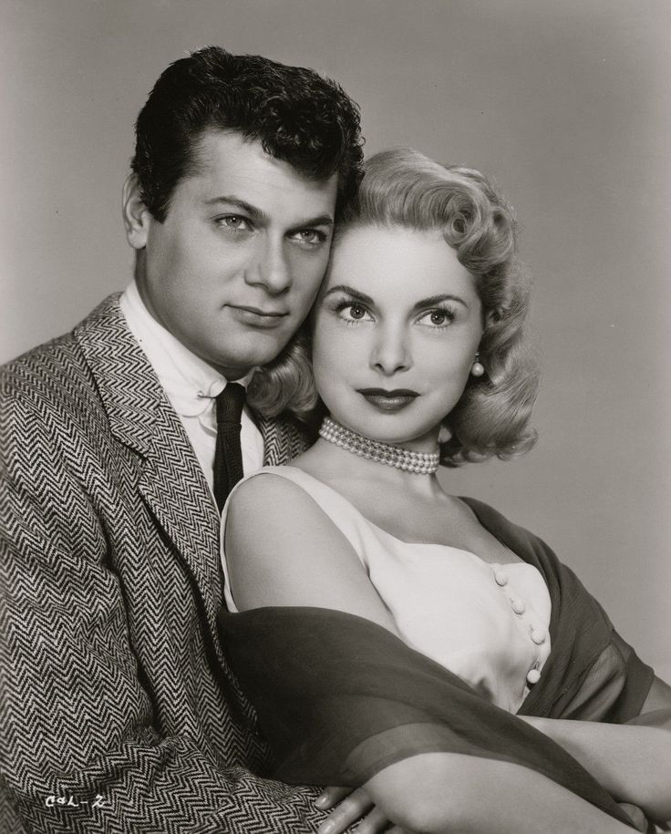 an old black and white photo of a man and woman posing for the camera with their arms around each other