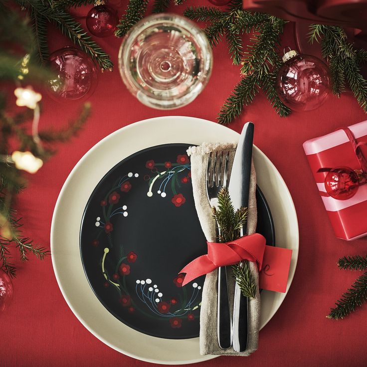 a plate with a fork and knife on it next to a christmas tree, wrapped in red ribbon