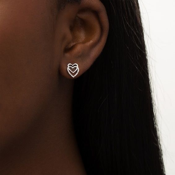 With double the love, these heart stud earrings add shimmer to most any attire. Created in sterling silver, each earring features a pair of heart-shaped outlines - one smaller and polished interlocked top-to-bottom with a larger outline. Beaded details and diamond accents glisten along the lower heart. Buffed to a brilliant luster, these post earrings secure comfortably with friction backs. Fine Jewelry Double Heart Earrings For Valentine's Day, Valentine's Day Fine Jewelry Double Heart Earrings, White Gold Double Heart Earrings For Pierced Ears, Sterling Silver Double Heart Earrings, Valentine's Day White Gold Pierced Heart Earrings, Silver Open Heart Cubic Zirconia Earrings, White Gold Double Heart Earrings Fine Jewelry, White Gold Double Heart Fine Jewelry Earrings, Fine Jewelry Open Heart Earrings For Anniversary