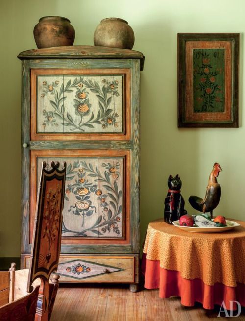 a table with two vases on top of it in front of a green wall