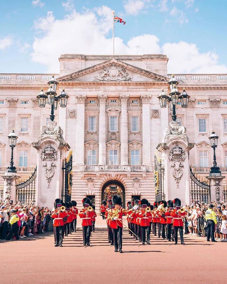 the guards are marching in front of buckingham palace, where people are gathered to watch