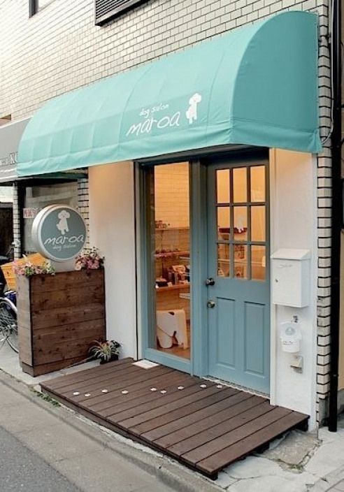 a store front with a blue awning and wooden steps leading up to the door