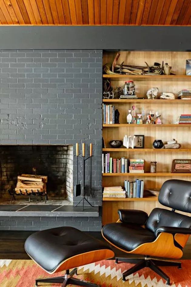 a living room with a fireplace, chair and bookshelf