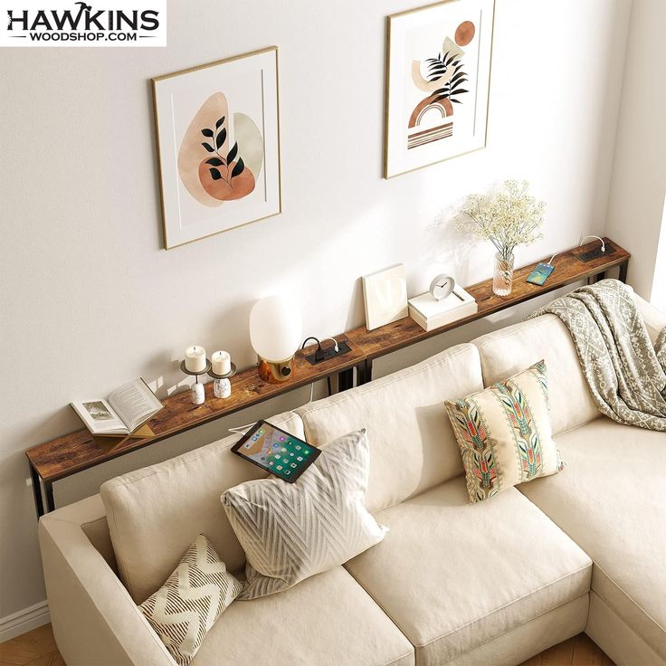 a living room with white couches and pictures on the wall above them, along with coffee table