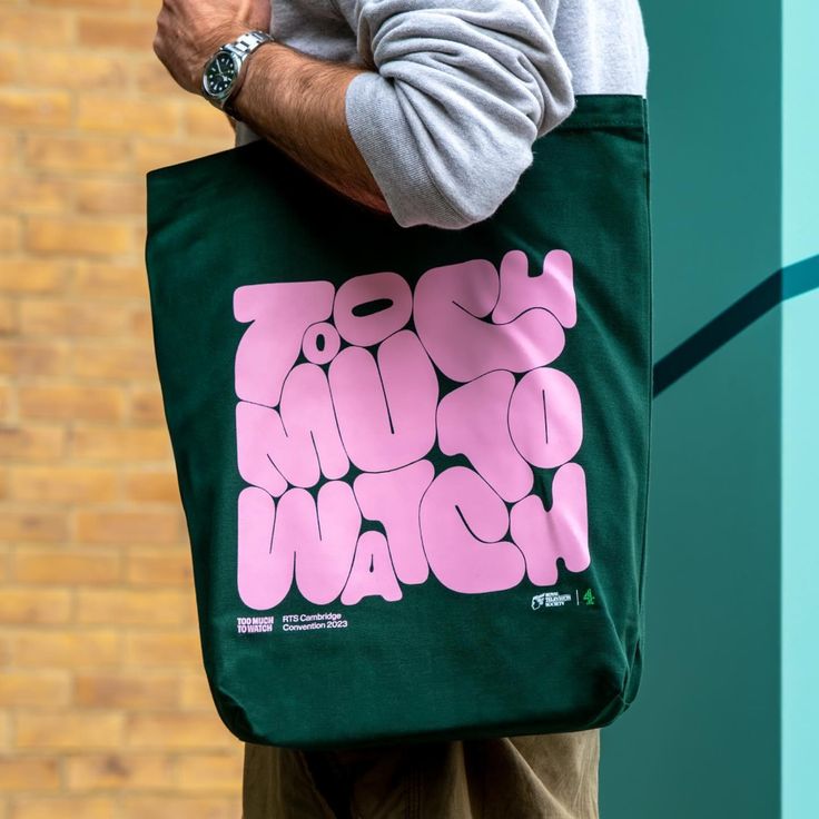 a man carrying a green tote bag with pink letters on it