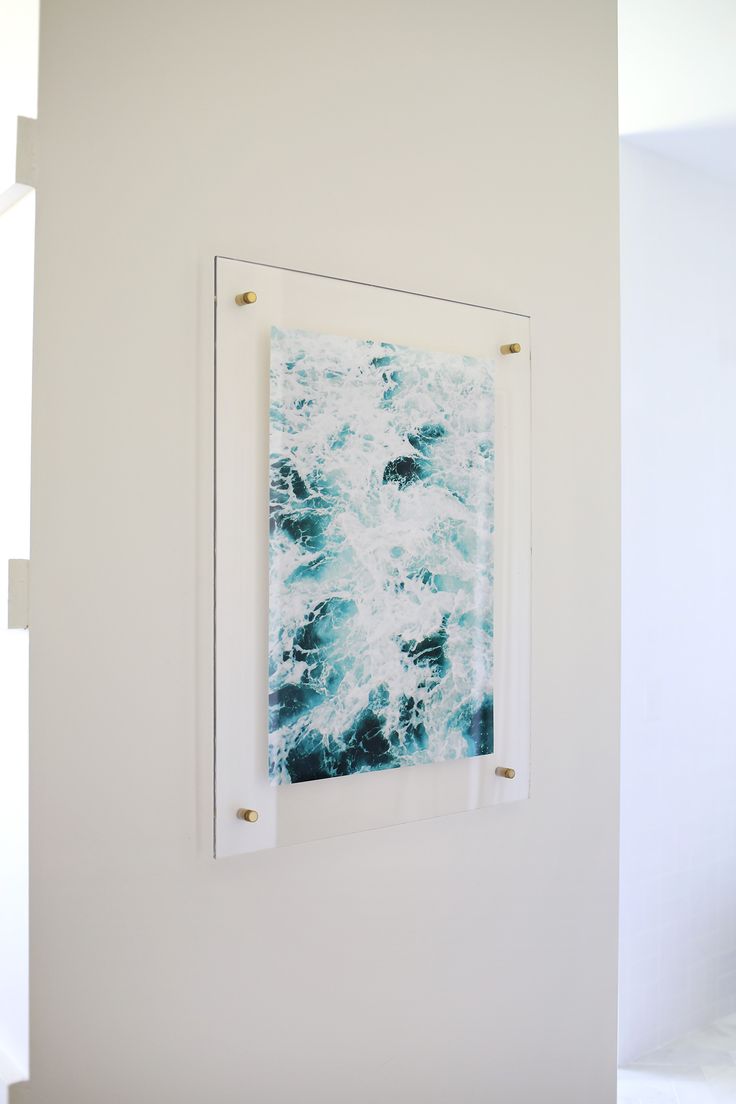 an abstract painting hangs on the wall next to a white chair in a bright room