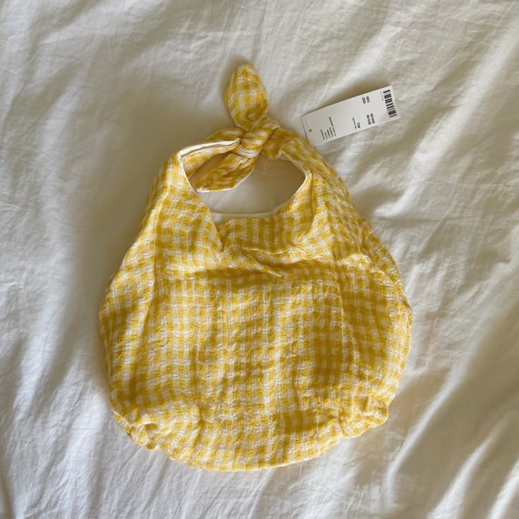 a yellow and white checkered bib laying on top of a bed