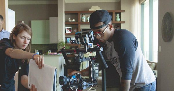 two people looking at something in front of a camera set up on a tripod