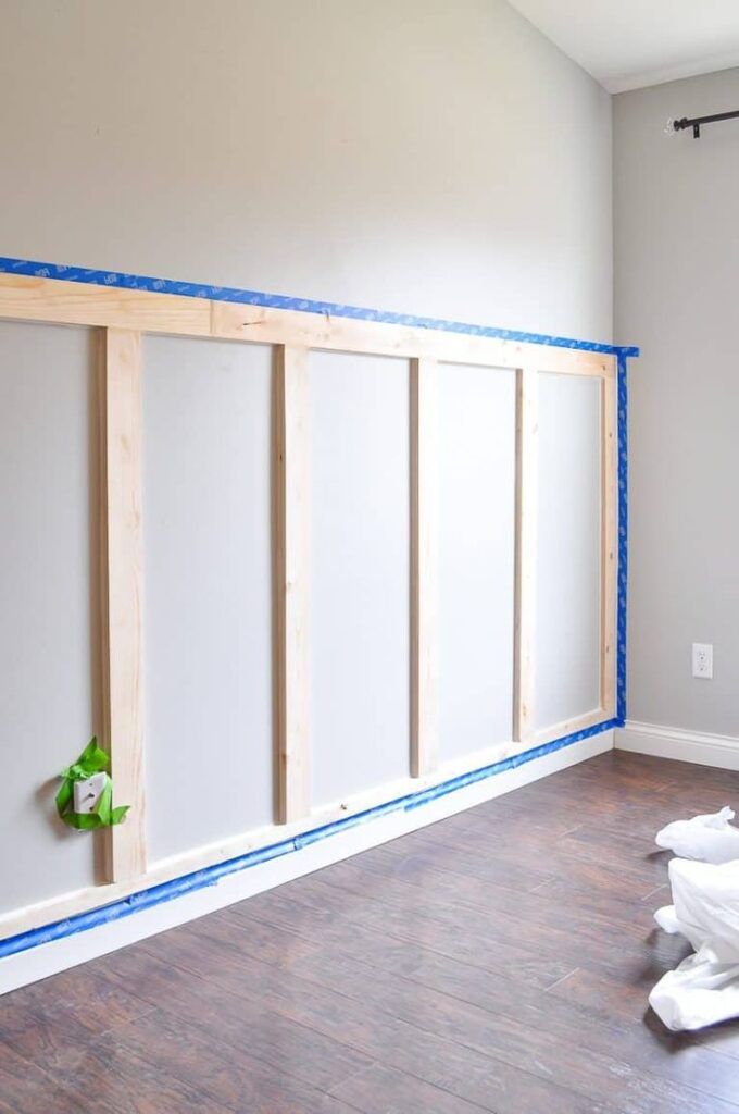 an empty room with white walls and blue tape on the wall next to wood flooring