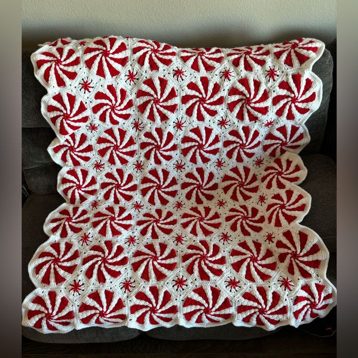 a red and white crocheted pillow sitting on top of a couch