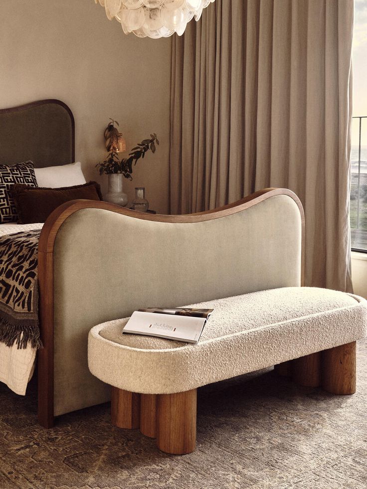 a bed sitting next to a window with curtains on the windowsill and a magazine laying on top of it