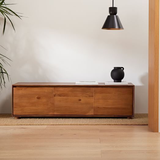 a black vase sitting on top of a wooden dresser next to a potted plant