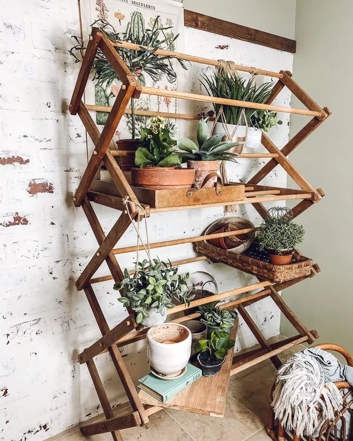 a wooden shelf filled with potted plants on top of a tiled floor