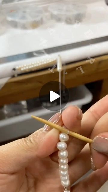 a person is holding a pencil and some pearls