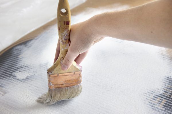 a person holding a paintbrush over a piece of paper