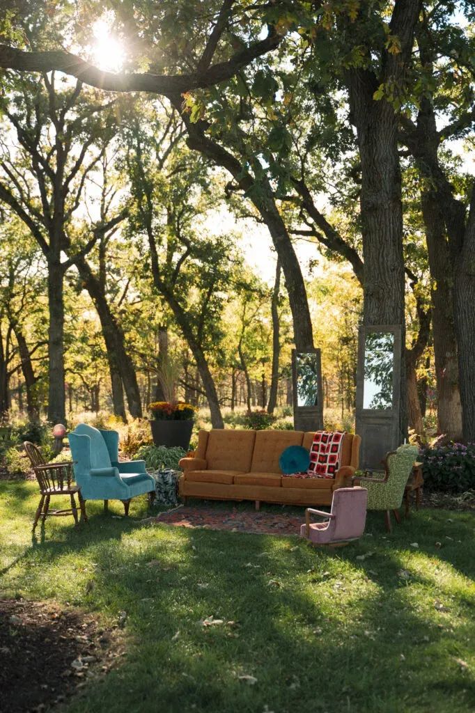 a couch and chairs in the grass under trees