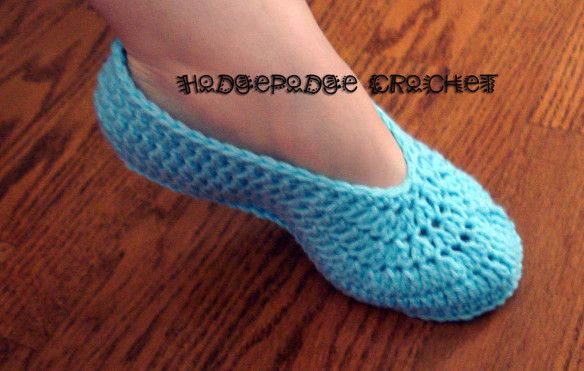 a close up of a person's feet wearing blue crochet slippers