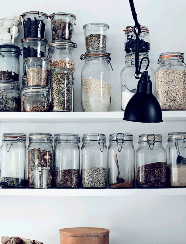 the shelves are filled with different types of spices and herbs in glass jars on top of each other