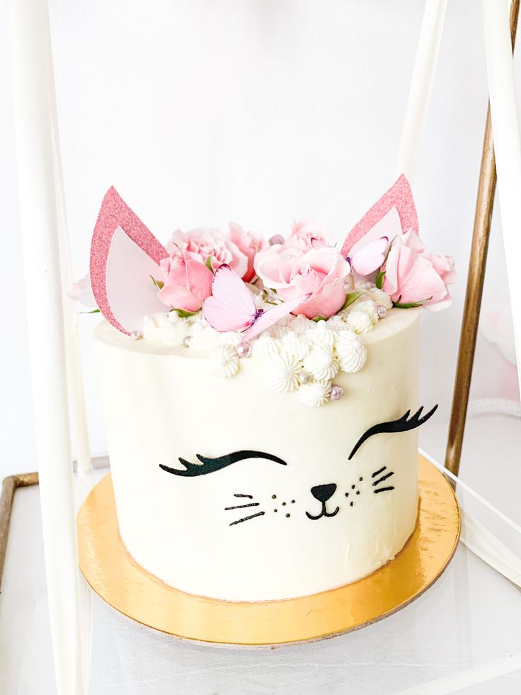 a white cake decorated with pink flowers and cat ears