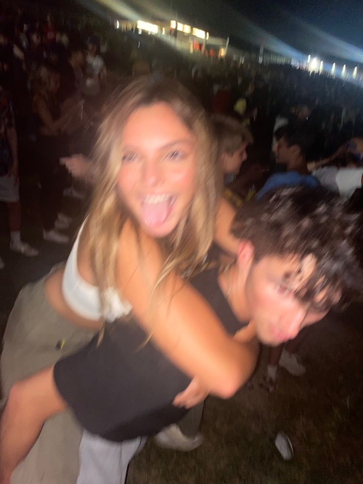 two people posing for the camera in front of an audience at a music festival with their arms around each other