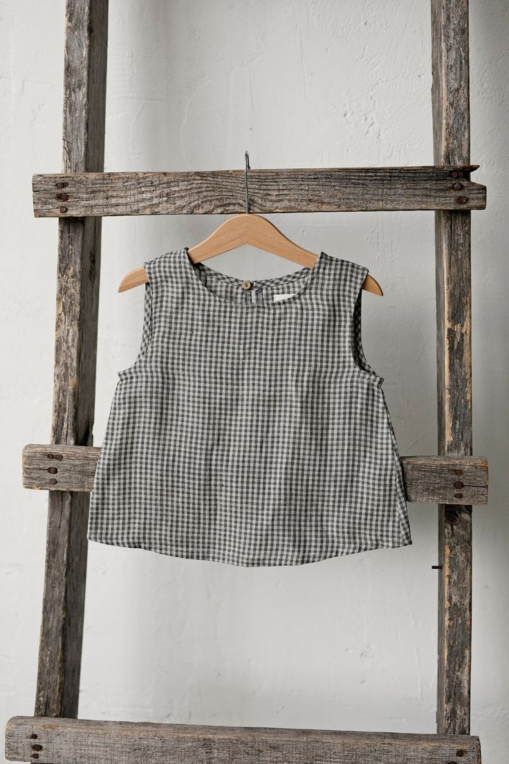 Sleeveless unisex shirt with a coconut button in the back is made of 100% soft medium weight linen. The shirt is suitable for both girls and boys.  Details: - Choose size and embroidery in the drop down menu - Colour: Grey gingham - Composition: 100% Oeko-Tex certified linen - Coconut button in the back - Medium weight linen - Unisex  - Relaxed silhouette - Linen care: machine wash gentle; tumble dry low, ironing optional - The price is for one shirt, other pictured items are not included Plaid Cotton Sleeveless Tank Top, Sleeveless Gingham Blouse For Summer, Sleeveless Gingham Cotton Top, Plaid Linen Tops For Spring, Summer Sleeveless Gingham Blouse, Spring Plaid Linen Top, Cotton Sleeveless Blouse For Spring, Sleeveless Cotton Blouse For Spring, Summer Gingham Cotton Tops