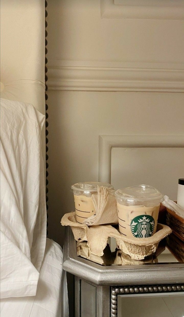 two cups of coffee sitting on top of a silver tray next to a mirror in a bedroom