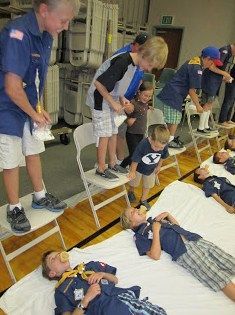 a group of people standing and laying on top of beds in a room with bunk beds