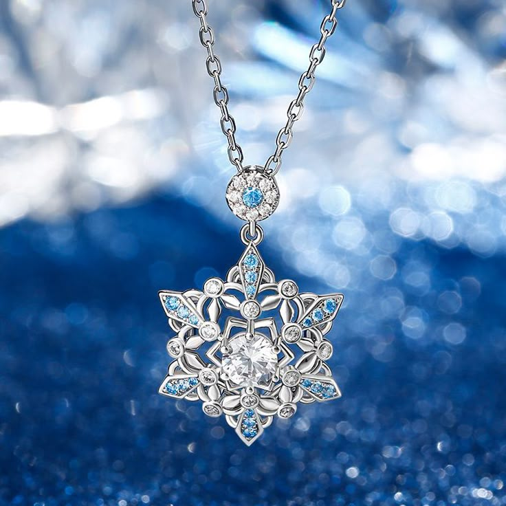 Calm, regal, and reserved, the mysterious beauty of this snowflake inspired necklace will leave you in awe. This snowflake necklace captures the beauty and intricacy of a snowflake gently falling from the sky during a winter snow. It designed is full of detailing, finished with sparkling blue sapphire stones to make it really shine on your neck. The glorious sparkle will turn heads and catch eyes. Give as a gift to someone at Christmas or treat yourself to remind you of this special time of year Snowflake Gemstone Jewelry, Snow Queen Gifts, Designer Necklace Aesthetic, Luxury Silver Snowflake Jewelry, Luxury Blue Crystal Necklace Elegant, Snow Flake Pendant Necklaces, Garnet Snowflake Necklace, Winter Snowflake Necklace With Black Tips, Unstoppable Love Aqua Marine Snowflake Necklace Zales