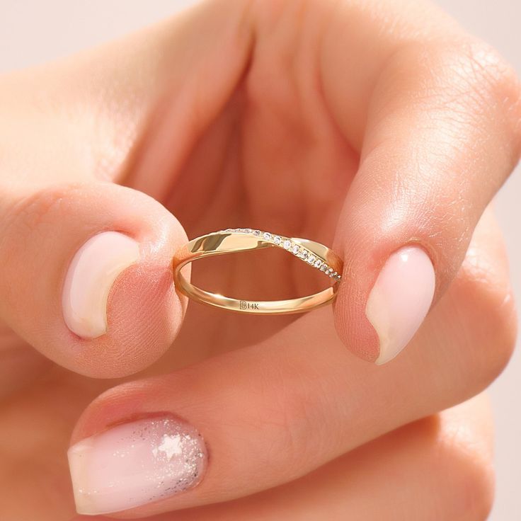 a woman's hand holding a gold ring with white glitter on the inside and outside