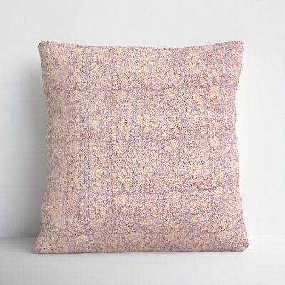 a pink and blue pillow sitting on top of a white table next to a wall