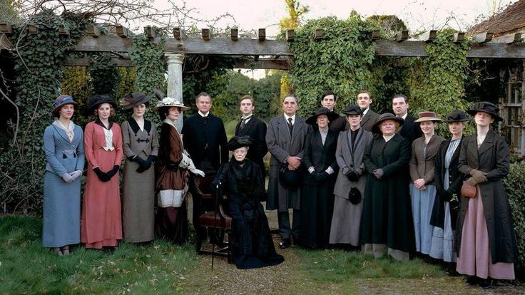 a group of people standing next to each other in front of an old fashioned building