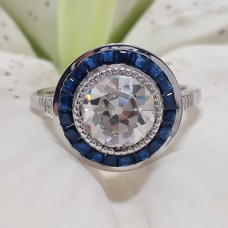 a diamond and blue sapphire ring sitting on top of a white flower