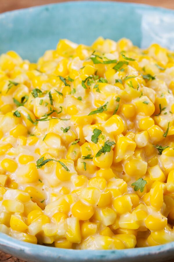 a blue bowl filled with corn and garnished with parsley on the side