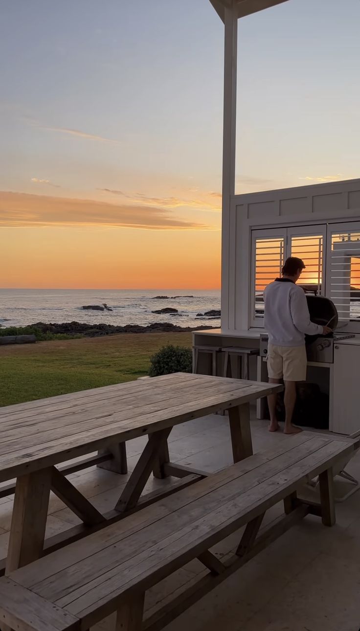 a man is standing at the kitchen counter looking out over the ocean