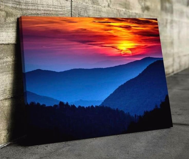 a painting on the side of a wooden wall with mountains in the background at sunset