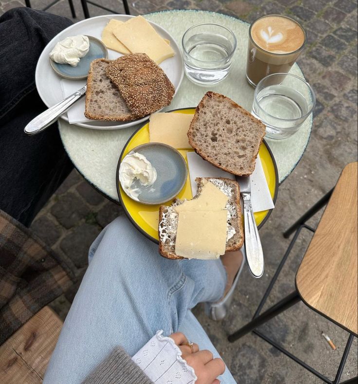 a person sitting at a table with bread and cheese on it