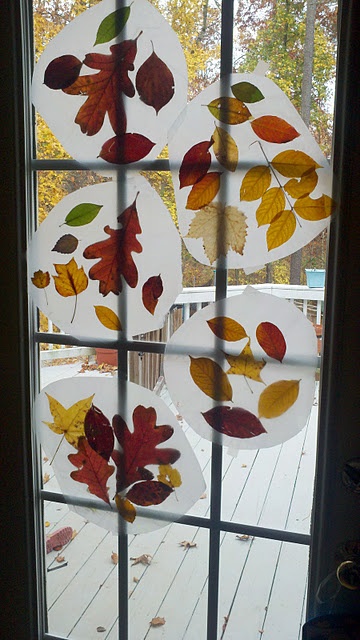 an open window with fall leaves painted on the glass and hanging from it's side