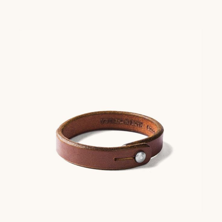 Description Constructed from the same leather used in our belts, our Single Wrap Wristband is a great option for those who don’t want to sport a lot of adornment. A simple leather band, we feel, is the perfect accent. Wristband Sizing Small/Medium: 7.75" in length, 15-15.5cm circumference Large/XLarge: 8.25" in length, 16-16.5cm circumference Width: .5" Details Constructed from 9-10oz. weights of the same Natural tooling leather used in our belts, each is punched out of a single strip of leather Simple Leather Bracelet, Leather Wristbands, Simple Leather, Leather Cuts, Genuine Leather Wallets, Wristbands, Leather Belts, Wrist Strap, Leather Band