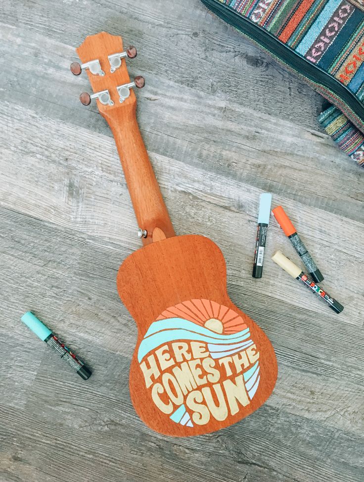 an orange ukulele with the words here comes the sun on it