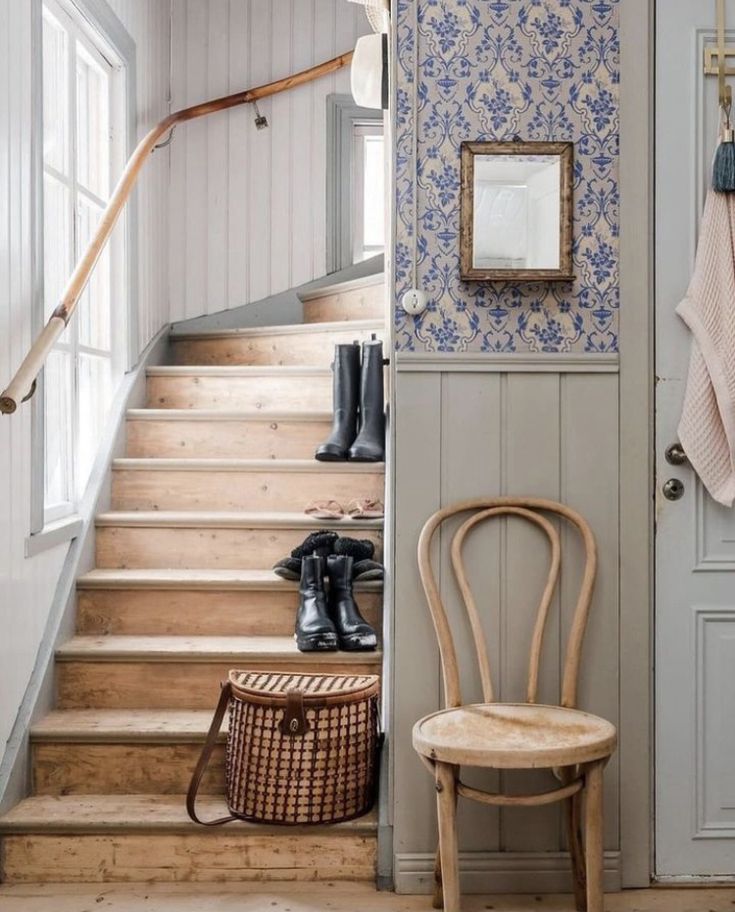 a wooden chair sitting in front of a stair case next to a window and door