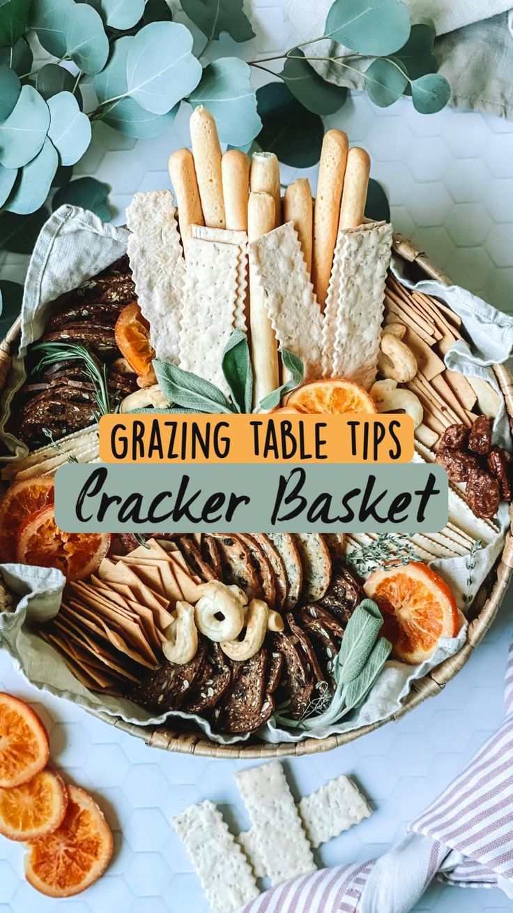 a basket filled with crackers and oranges on top of a blue table cloth