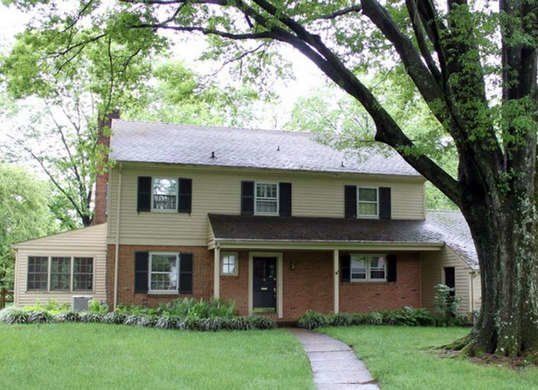 a large house sitting in the middle of a lush green field next to a tree