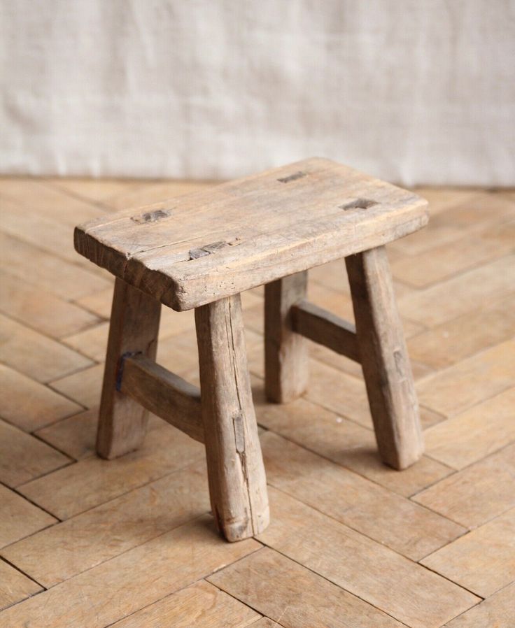 a small wooden stool sitting on top of a tile floor