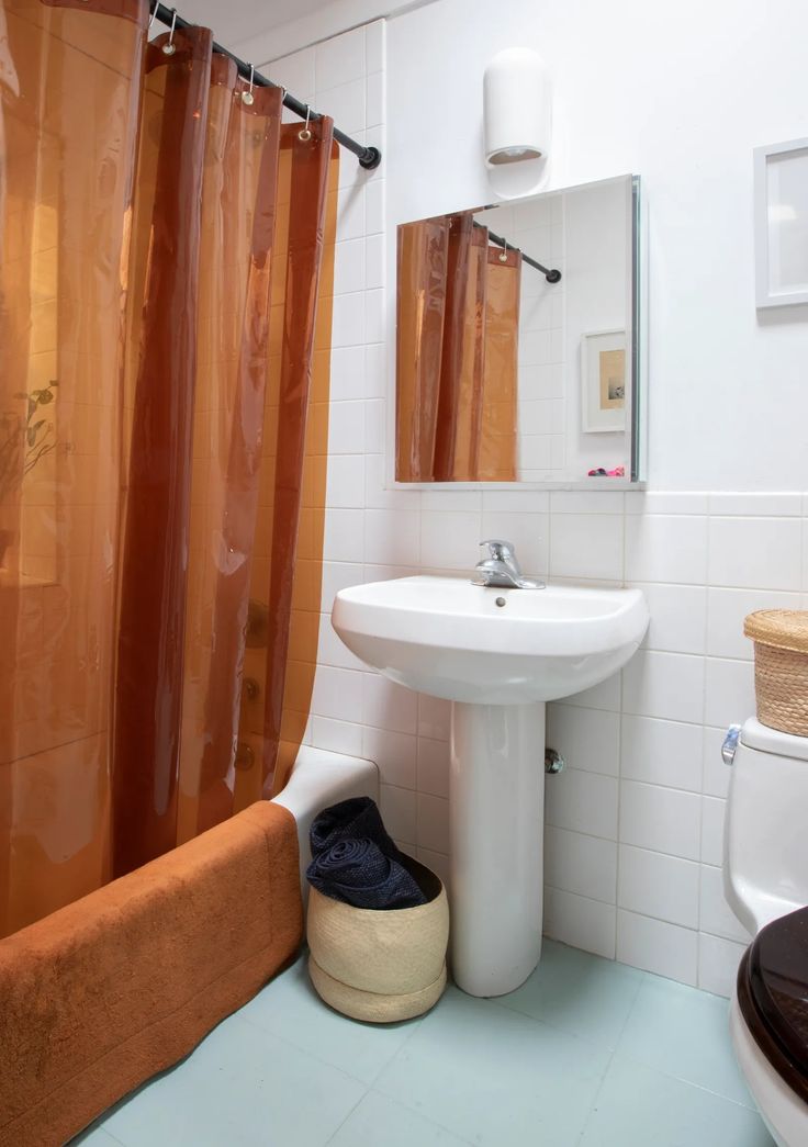 a bathroom with a toilet, sink and shower curtain in it's center area