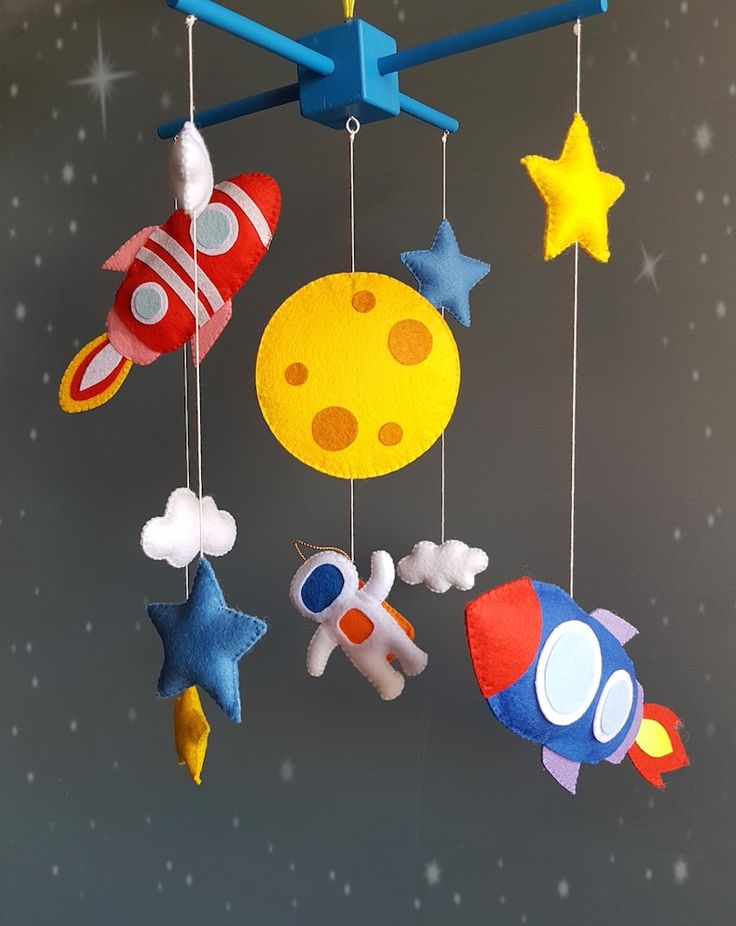 a mobile with various toys hanging from it's strings in the shape of rockets, planets and stars