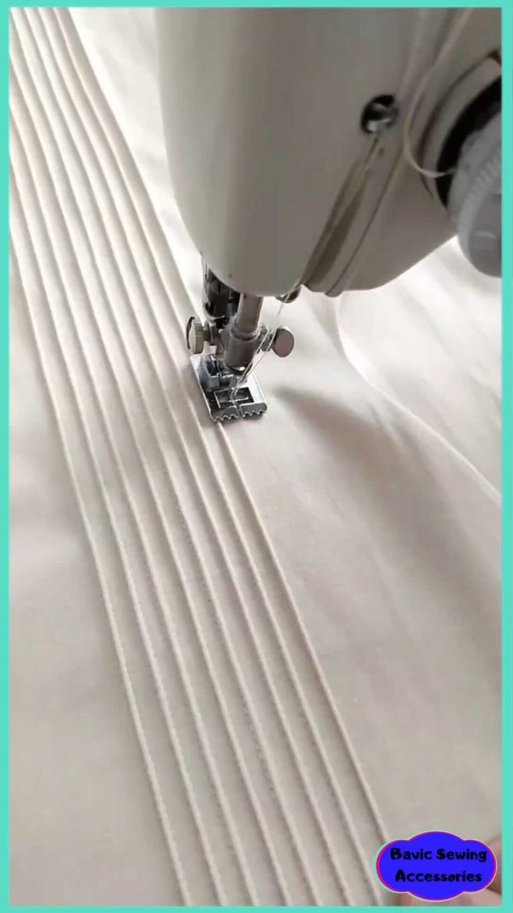 the sewing machine is working on some white material with lines in it's center