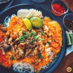 a blue plate topped with lots of food next to glasses and sauces on a table